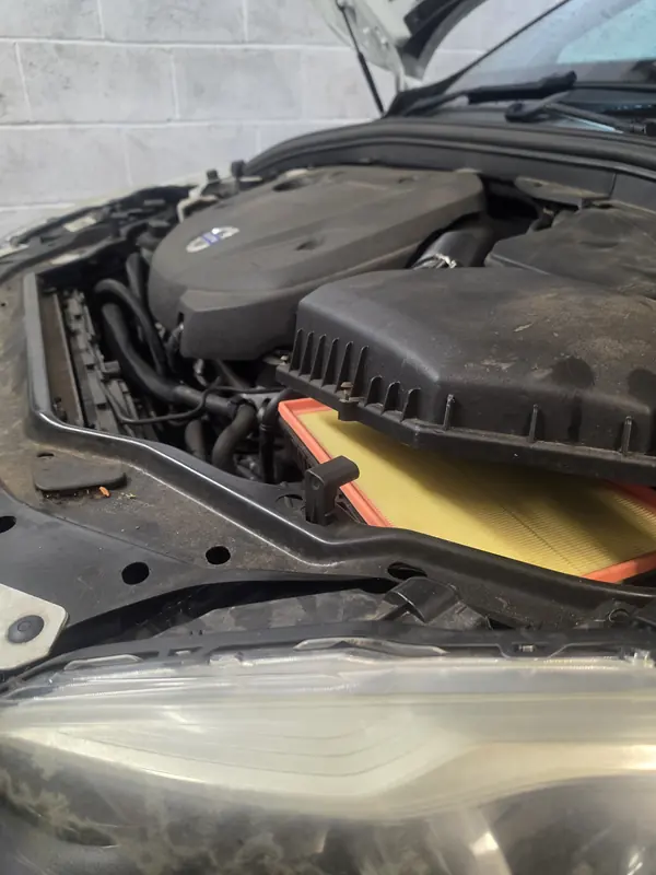 Engine bay of a 2014 Volvo XC60 during a full service at Village Motor Center in Warrington, with the new air filter going in